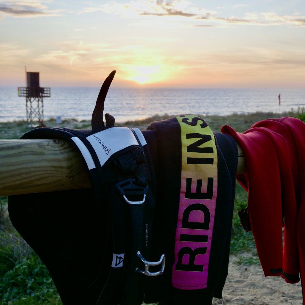 Windsurf clothing and equipment hanging at Tarifa beach in sunset 